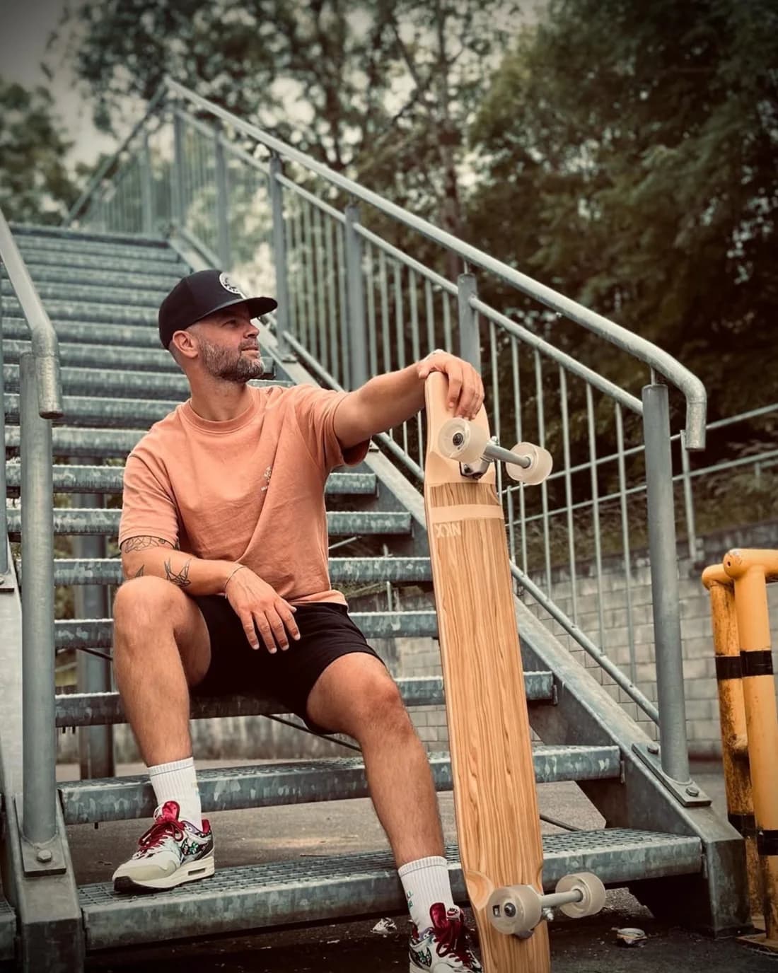 Twan Swanen sitting on a flight of steps with a longboard